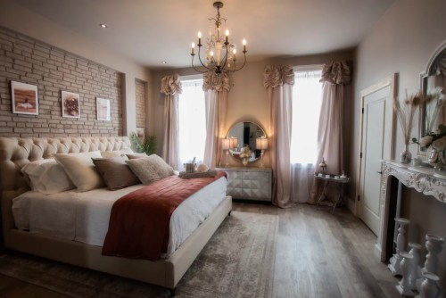 Cozy bedroom featuring a tufted bed, elegant decor, large windows, and soft lighting for a warm ambiance.