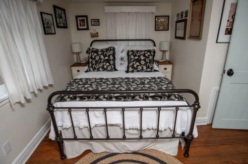 Cozy bedroom featuring a metal bed frame, floral bedding, nightstands, and framed photos on the walls.