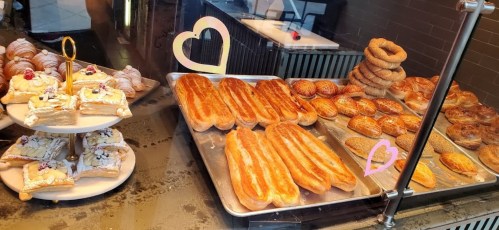 A display of assorted pastries, including croissants, danishes, and sweet rolls, arranged on trays and plates.
