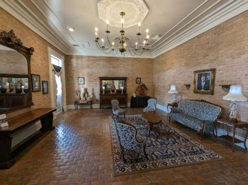 Elegant room with brick walls, vintage furniture, a chandelier, and decorative mirrors. Cozy and inviting atmosphere.