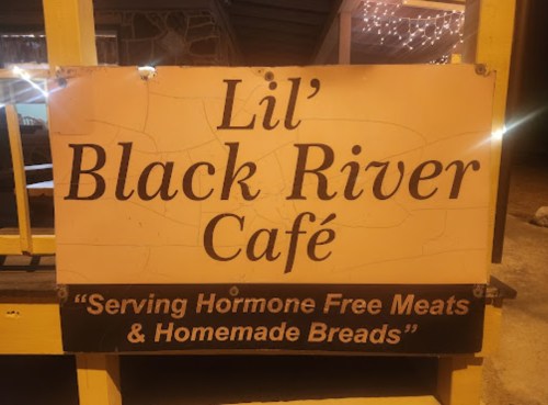Sign for Lil' Black River Café, promoting hormone-free meats and homemade breads. Warm, inviting atmosphere.