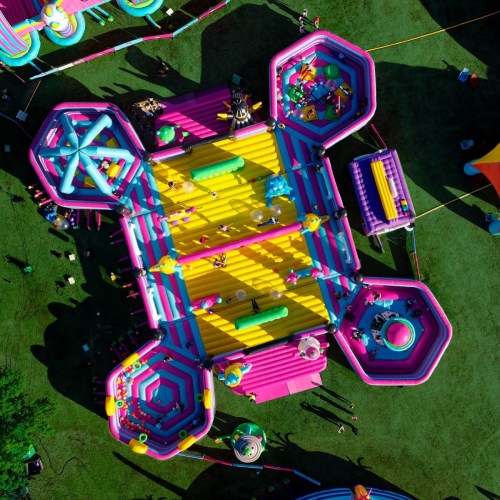 Aerial view of colorful inflatable play structures with children playing on a sunny day.