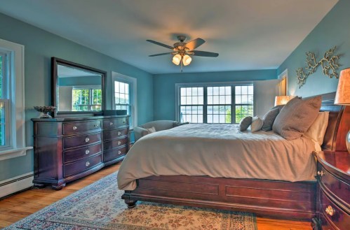 Cozy bedroom with a large bed, dresser, and windows, featuring soft lighting and a warm color palette.