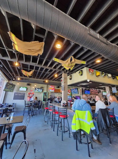 Interior of a casual restaurant with hanging decorations, bar seating, and patrons enjoying their meals.