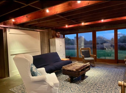 Cozy living room with a blue sofa, wooden coffee table, and large windows overlooking a scenic outdoor view.