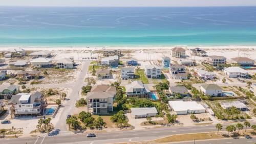 Aerial view of coastal homes along a sandy beach with turquoise waters in the background.