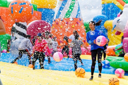 A colorful inflatable playground filled with bubbles, children playing with beach balls and enjoying the fun atmosphere.