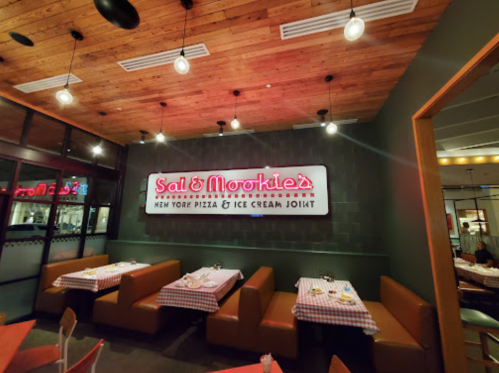 Interior of Sal & Mookie's, featuring a wooden ceiling, cozy booths, and a neon sign for New York pizza and ice cream.