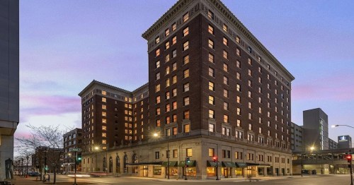 Historic brick hotel building at dusk, featuring multiple stories and illuminated windows.