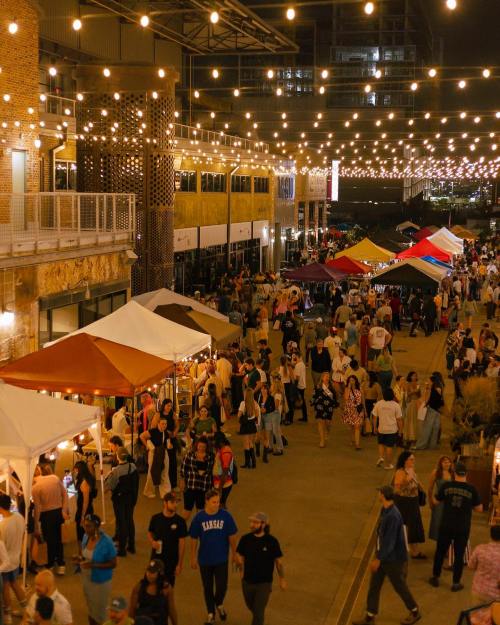 A bustling night market scene with crowds, food stalls, and string lights illuminating the atmosphere.