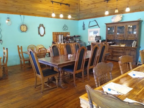 Cozy restaurant interior with wooden tables, chairs, and a blue wall, featuring rustic decor and warm lighting.