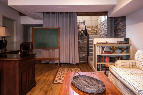 Cozy basement space with a desk, bookshelf, chalkboard, and a comfortable seating area.