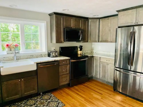 Modern kitchen with dark wood cabinets, stainless steel appliances, a farmhouse sink, and hardwood flooring.