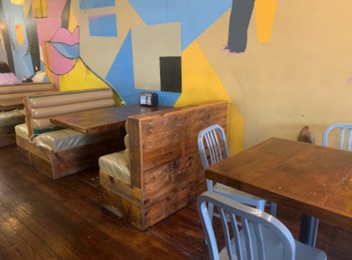 Colorful restaurant interior featuring wooden tables and booths against a vibrant mural.