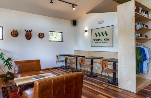 Cozy interior of a cafe with wooden floors, leather seating, and a display of merchandise on the wall.