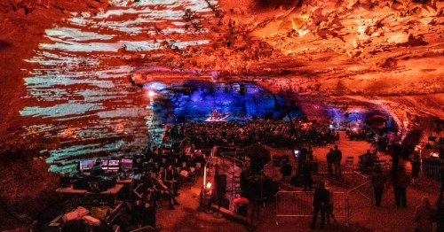 A vibrant cave concert scene with colorful lights illuminating the rock formations and an audience enjoying the performance.