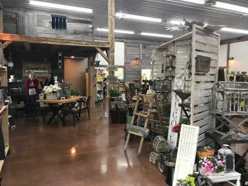 A rustic store interior with wooden decor, tables, and various plants and home goods displayed throughout.