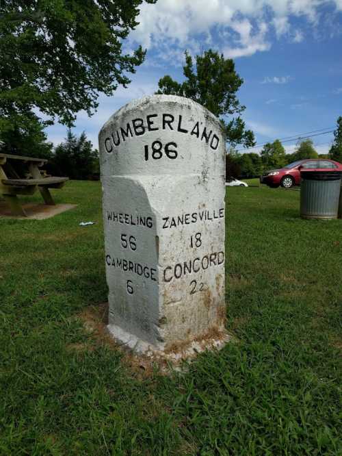 Milestone marking distances to Cumberland, Wheeling, Zanesville, Cambridge, and Concord, set in a grassy area.