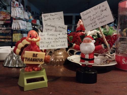 A turkey and Santa figurine on a table, with a note about gratitude and a request for help with a fundraiser.