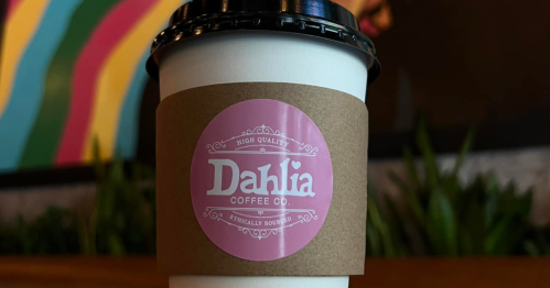 A coffee cup with a pink label reading "Dahlia Coffee Co." sits against a colorful background.