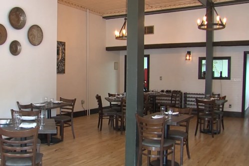 Interior of a restaurant featuring wooden tables, chairs, and decorative wall plates, with a warm, inviting atmosphere.