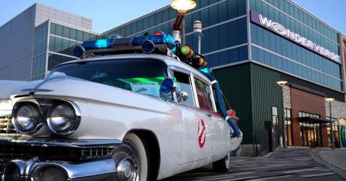 A vintage white car with police lights parked outside a building labeled "Wonderverse."