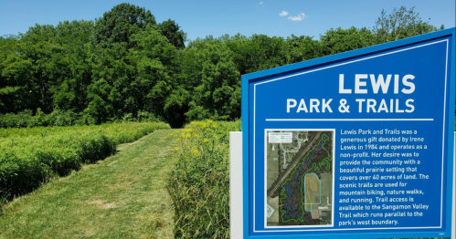 Sign for Lewis Park & Trails, featuring a scenic path through lush greenery and information about the park's features.