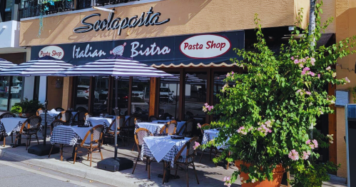 Exterior of "Scolapasta" Italian Bistro with outdoor seating, checkered tablecloths, and potted plants.