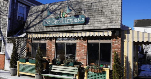 A cozy restaurant called "The Great Impasta" with a brick exterior and green seating, surrounded by snow.