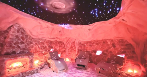 A cozy, dimly lit room with stone walls, lounge chairs, and a starry ceiling, creating a relaxing atmosphere.