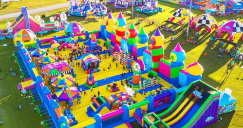 A vibrant, colorful inflatable amusement park filled with various slides, bounce houses, and attractions.