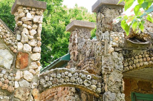 Close-up of a weathered stone structure with unique textures and greenery in the background.