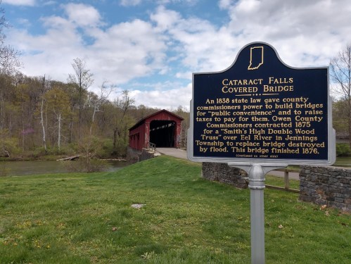 Sign for Cataract Falls Covered Bridge, detailing its history and construction, with a scenic view of the bridge and river.