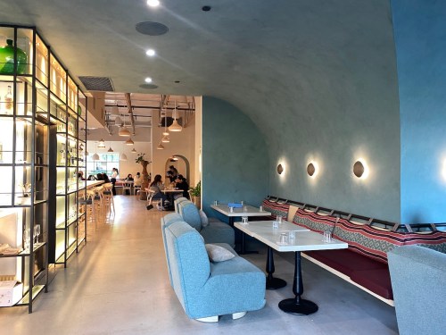 A modern café interior with curved walls, cozy seating, and a bar area, featuring warm lighting and a relaxed atmosphere.