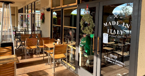 Exterior view of a restaurant named "Made in Italy," featuring outdoor seating and a festive wreath on the door.