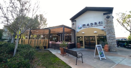 Exterior view of "Madrí" restaurant featuring a patio, stone accents, and a welcoming entrance.