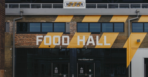 Exterior of a food hall with large "FOOD HALL" text and a "NOW OPEN" sign above the entrance.