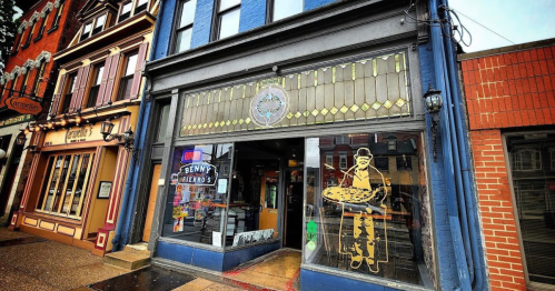 A storefront with a blue facade and large window displaying a pizza-themed graphic and the name "Benny's."