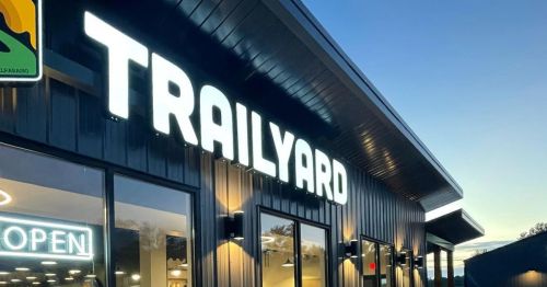 Signage of "TRAILYARD" illuminated on a modern building exterior at dusk.
