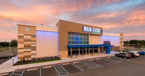 Exterior of a Main Event entertainment center at sunset, featuring modern architecture and colorful lighting.