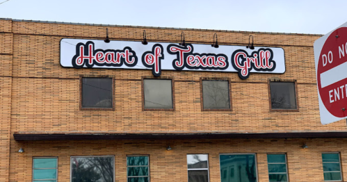 Sign for "Heart of Texas Grill" on a brick building, with a red and white color scheme.