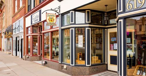 A row of storefronts featuring an Italian restaurant with an "Open" sign, set in a charming urban area.