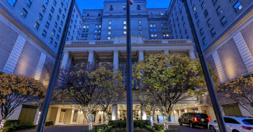 Historic hotel entrance at dusk, featuring elegant architecture and illuminated trees.
