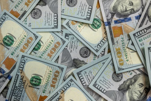 A close-up view of scattered hundred-dollar bills on a surface.