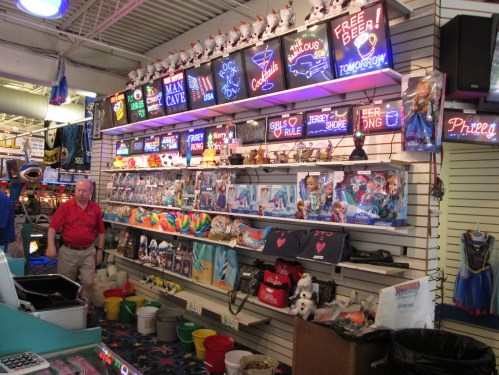 A colorful shop display featuring neon signs, souvenirs, and beach-themed merchandise, with a man browsing.