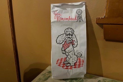 A decorative paper bag featuring a cartoon poodle with a scarf, captioned "You Remembered" in red lettering.
