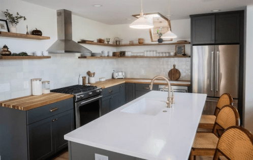 Modern kitchen with gray cabinets, wooden shelves, a large island, and stainless steel appliances. Bright and inviting space.