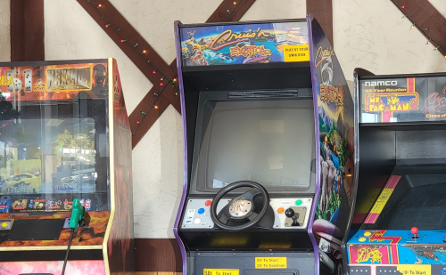An arcade cabinet for the game "Cruis'n Exotica," featuring a steering wheel and a blank screen.