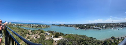 A panoramic view of a coastal town with waterways, boats, and a clear blue sky, taken from a high vantage point.