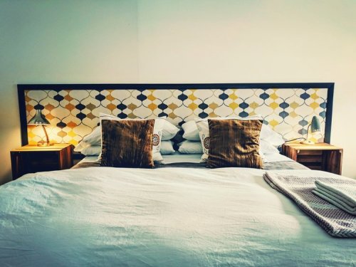 Cozy bedroom with a patterned headboard, two lamps, and decorative pillows on a neatly made bed.